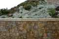 Beautifully folded retaining wall with a granite attic with small joints. brown beige yellow irregular gneiss stone holding a slop Royalty Free Stock Photo