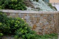 Beautifully folded retaining wall with a granite attic with small joints. brown beige yellow irregular gneiss stone holding a slop Royalty Free Stock Photo