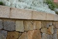 Beautifully folded retaining wall with a granite attic with small joints. brown beige yellow irregular gneiss stone holding a slop Royalty Free Stock Photo