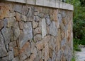 Beautifully folded retaining wall with a granite attic with small joints. brown beige yellow irregular gneiss stone holding a slop