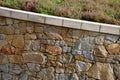 Beautifully folded retaining wall with a granite attic with small joints. brown beige yellow irregular gneiss stone holding a slop Royalty Free Stock Photo