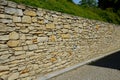 Beautifully folded retaining wall with a granite attic with small joints. brown beige yellow irregular gneiss stone holding a slop Royalty Free Stock Photo