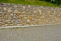 Beautifully folded retaining wall with a granite attic with small joints. brown beige yellow irregular gneiss stone holding a slop Royalty Free Stock Photo