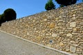 Beautifully folded retaining wall with a granite attic with small joints. brown beige yellow irregular gneiss stone holding a slop Royalty Free Stock Photo