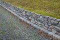 Beautifully folded retaining wall with a granite attic with small joints. brown beige yellow irregular gneiss stone holding a slop Royalty Free Stock Photo