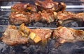 Beautifully fried pork steaks on skewers smoke on hot coals