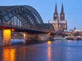The beautifully illuminated cathedral in the German city of Cologne and the Hohenzollern Bridge over the river Rhine at dawn
