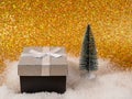 A beautifully packaged gift box and decorative Christmas trees stand on white snow. Royalty Free Stock Photo