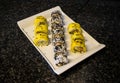 Beautifully presented and freshly prepared sweet mango sushi roll served on a white plate, black table Royalty Free Stock Photo