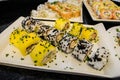 Beautifully presented and freshly prepared sweet mango sushi roll served on a white plate, black table Royalty Free Stock Photo