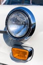 Close-up of the round headlamps and orange turn signal of a white classic car. Royalty Free Stock Photo