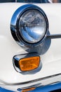 Close-up of the round headlamps and orange turn signal of a white classic car. Royalty Free Stock Photo