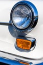 Close-up of the round headlamps and orange turn signal of a white classic car. Royalty Free Stock Photo