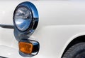 Close-up of the round headlamps and orange turn signal of a white classic car. Royalty Free Stock Photo