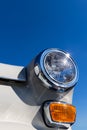 Close-up of the round headlamps and orange turn signal of a white classic car. Royalty Free Stock Photo