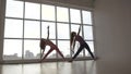 Beautifully-shot young women practicing extended triangle yoga pose together