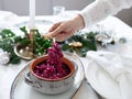 Beautifully styled, festive table setting, female hand serving red cabbage, natural table runner