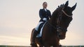 a beautifully trained smiling young woman rides a horse with her head bowed