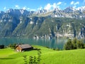 Beautifully view with a turquoise blue swiss lake with snow-covered mountains and wooden houses