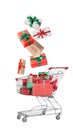 Beautifully wrapped gift boxes falling into metal shopping cart on white background Royalty Free Stock Photo