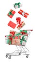 Beautifully wrapped gift boxes falling into metal shopping cart on white background Royalty Free Stock Photo
