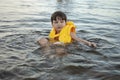 Beautifyl cute little kid boy in the yellow life jacket on a beach lifestyle picture