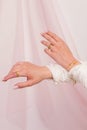 Beautuful woman hands with ring and bracelets set against a pink curtain
