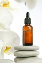 Beauty and aromatherapy.Massage oil and massage stones.glass bottle with oil on stones and white orchid flower .Spa and Royalty Free Stock Photo