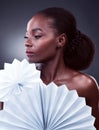 Beauty as precious as a pearl. Studio shot of a beautiful young woman posing with origami fans against a black