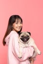 Beauty Asian young woman holding dog pug breed on her arm smile and happiness,Owner hug her cute pet dog with love on pink Royalty Free Stock Photo