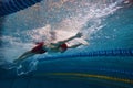 Beauty of athleticism in action. Dynamic image of young man, athlete in motion, swimming in s pool indoors, training Royalty Free Stock Photo