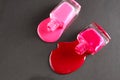 Beauty background two bottles of nail polish bottles red or burgundy pink spill poured on the table on a black background close-up Royalty Free Stock Photo