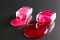 Beauty background two bottles of nail polish bottles red or burgundy pink spill poured on the table on a black background close-up Royalty Free Stock Photo