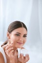 Beauty. Beautiful Woman Applying Face Cream On Soft Facial Skin Royalty Free Stock Photo