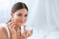 Beauty. Beautiful Woman Applying Face Cream On Soft Facial Skin Royalty Free Stock Photo