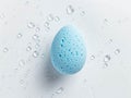 Beauty blender on a white background with water drops.