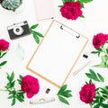 Beauty blog concept. Blogger or freelancer workspace desk with clipboard, notebook, retro camera, peonies and pen on white backgro