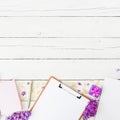 Beauty blog concept with clipboard, notebook, lilac, gift box and accessories on wooden background. Flat lay, top view. Royalty Free Stock Photo