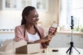 Beauty Blogging. Happy Young African Influencer Lady Recording Makeup Review In Kitchen Royalty Free Stock Photo