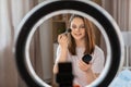 girl blogger with ring light applying make up