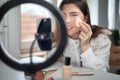 beauty blogging, technology and people concept portrait of a happy smiling girl blogger with ring light and smartphone applying