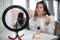 beauty blogging, technology and people concept portrait of a happy smiling girl blogger with ring light and smartphone applying