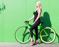 Beauty blonde girl with long hair in a black tight-fitting outfit and sneakers posing with a fashionable fix