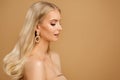 Beauty Blonde Hair Model Face over Beige. Elegant Woman Portrait with Gold Earring. Fashion Girl with Natural Make up, Gloss Skin Royalty Free Stock Photo