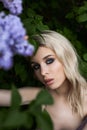 Beauty blonde woman in summer in a lilac Bush. Beauty Portrait of a girl in purple flowers, beautiful makeup Royalty Free Stock Photo