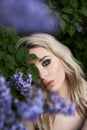 Beauty blonde woman in summer in a lilac Bush. Beauty Portrait of a girl in purple flowers, beautiful makeup Royalty Free Stock Photo