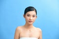 Beauty, bodycare and people concept - beautiful young woman with bare shoulder over blue background