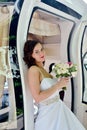 Beauty bride in bridal gown with bouquet and lace veil in the car