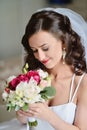 Beauty bride in bridal gown with bouquet and lace veil indoors Royalty Free Stock Photo