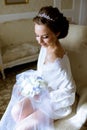 Beauty bride in dressing gown with bouquet indoors